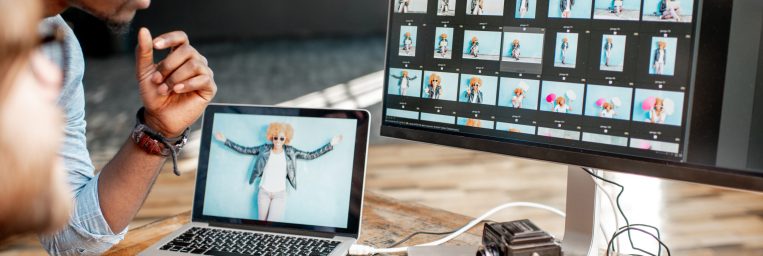 Two male photographers choosing woman's portraits at the working place with two computers in the studio
